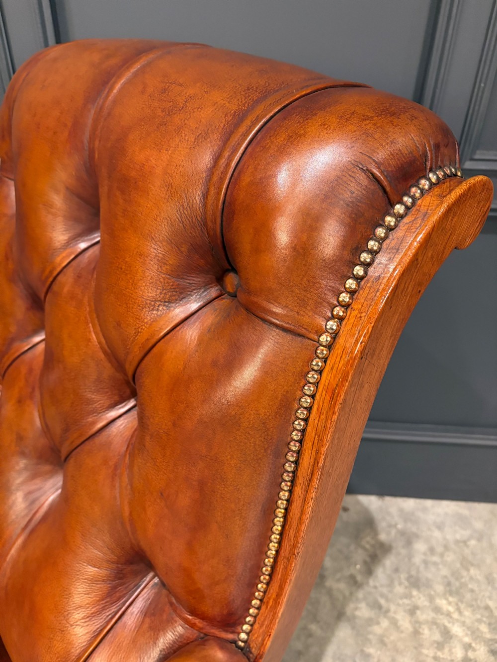 A pair of antique oak armchairs upholstered in deep-buttoned chestnut brown leather with turned front legs and brass castors. View VIII
