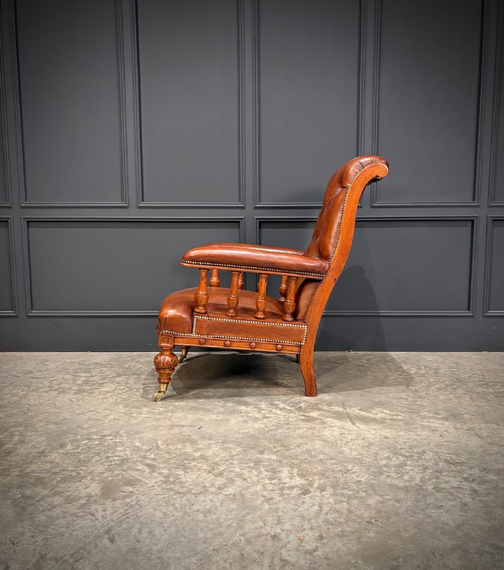 A pair of antique oak armchairs upholstered in deep-buttoned chestnut brown leather with turned front legs and brass castors. View XI