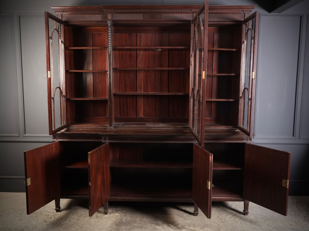 A large mahogany breakfront bookcase featuring upper glazed doors with astragal tracery above lower cupboards with oval flame mahogany veneer panels. View III