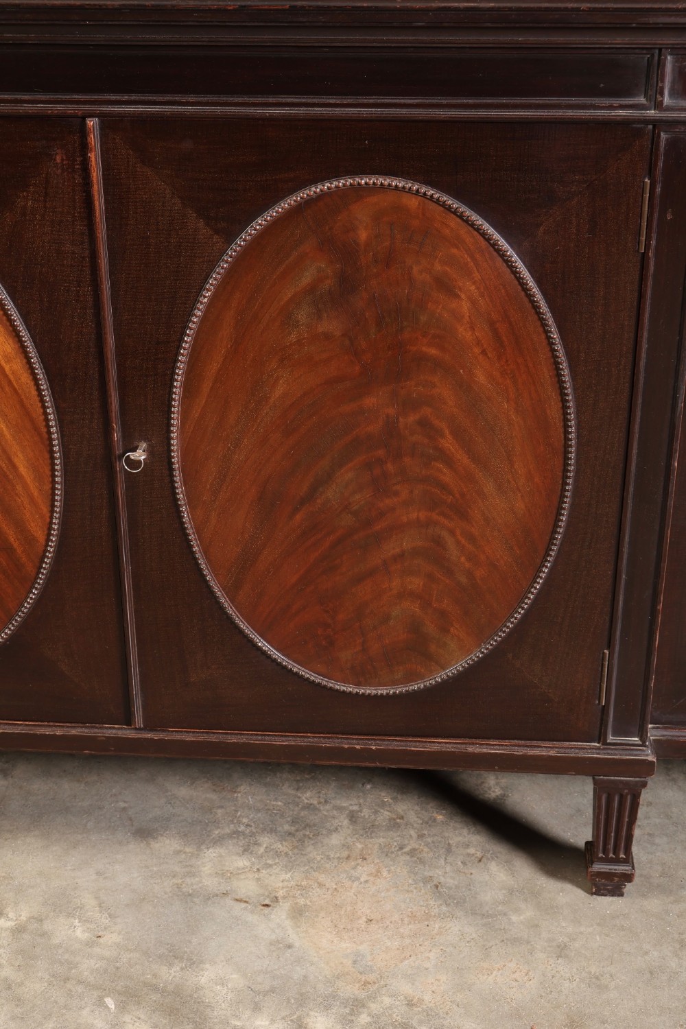 A large mahogany breakfront bookcase featuring upper glazed doors with astragal tracery above lower cupboards with oval flame mahogany veneer panels. View V