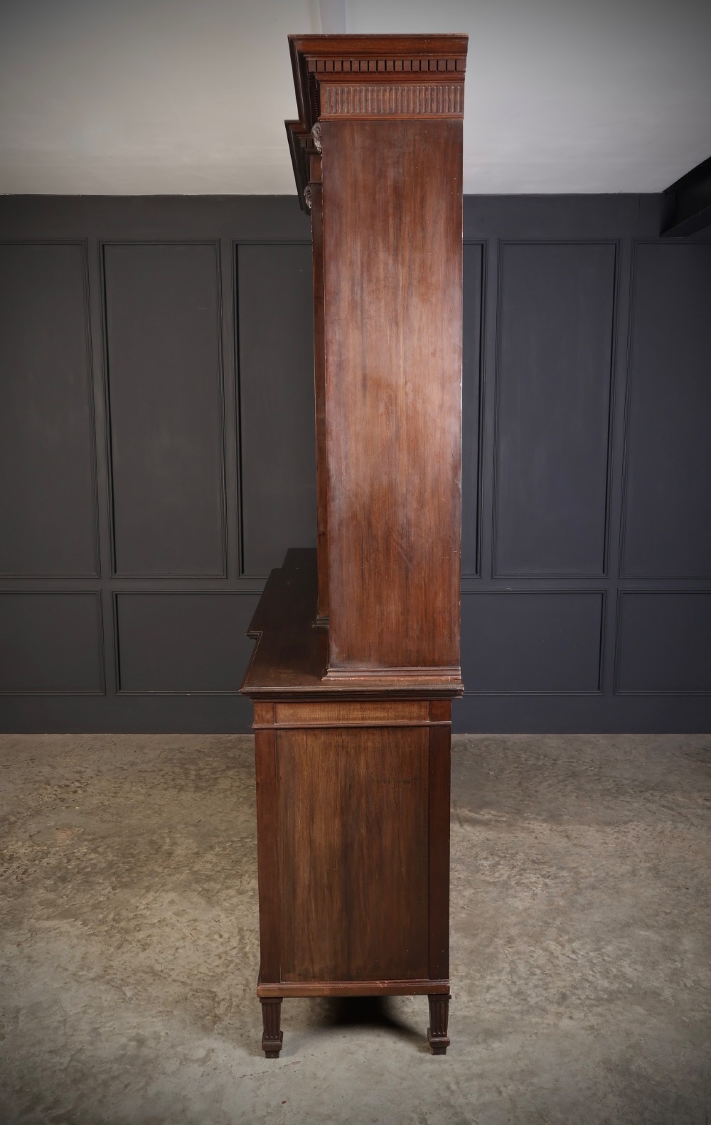 A large mahogany breakfront bookcase featuring upper glazed doors with astragal tracery above lower cupboards with oval flame mahogany veneer panels. View VII