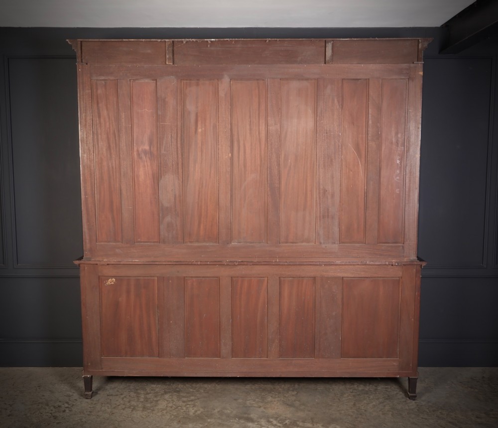 A large mahogany breakfront bookcase featuring upper glazed doors with astragal tracery above lower cupboards with oval flame mahogany veneer panels. View VIII