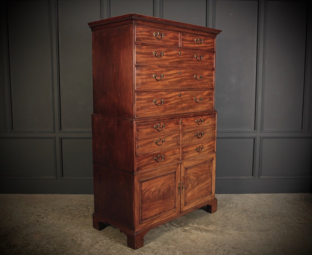 An 18th-century Georgian flame mahogany tallboy chest on chest featuring brass handles, upper drawers, and lower cupboard doors.