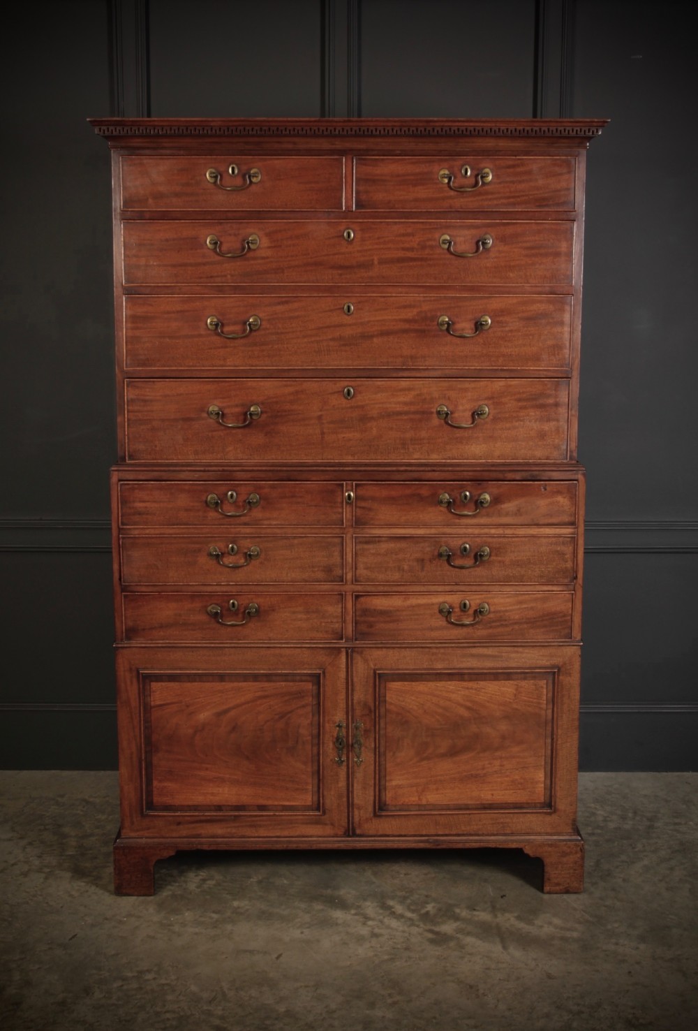 An 18th-century Georgian flame mahogany tallboy chest on chest featuring brass handles, upper drawers, and lower cupboard doors. View II