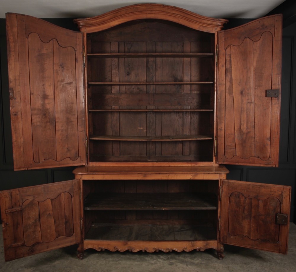 An 18th-century French Provincial two-tier cherry wood cupboard featuring moulded panel doors, long brass hinges, and a curved top cornice. View III