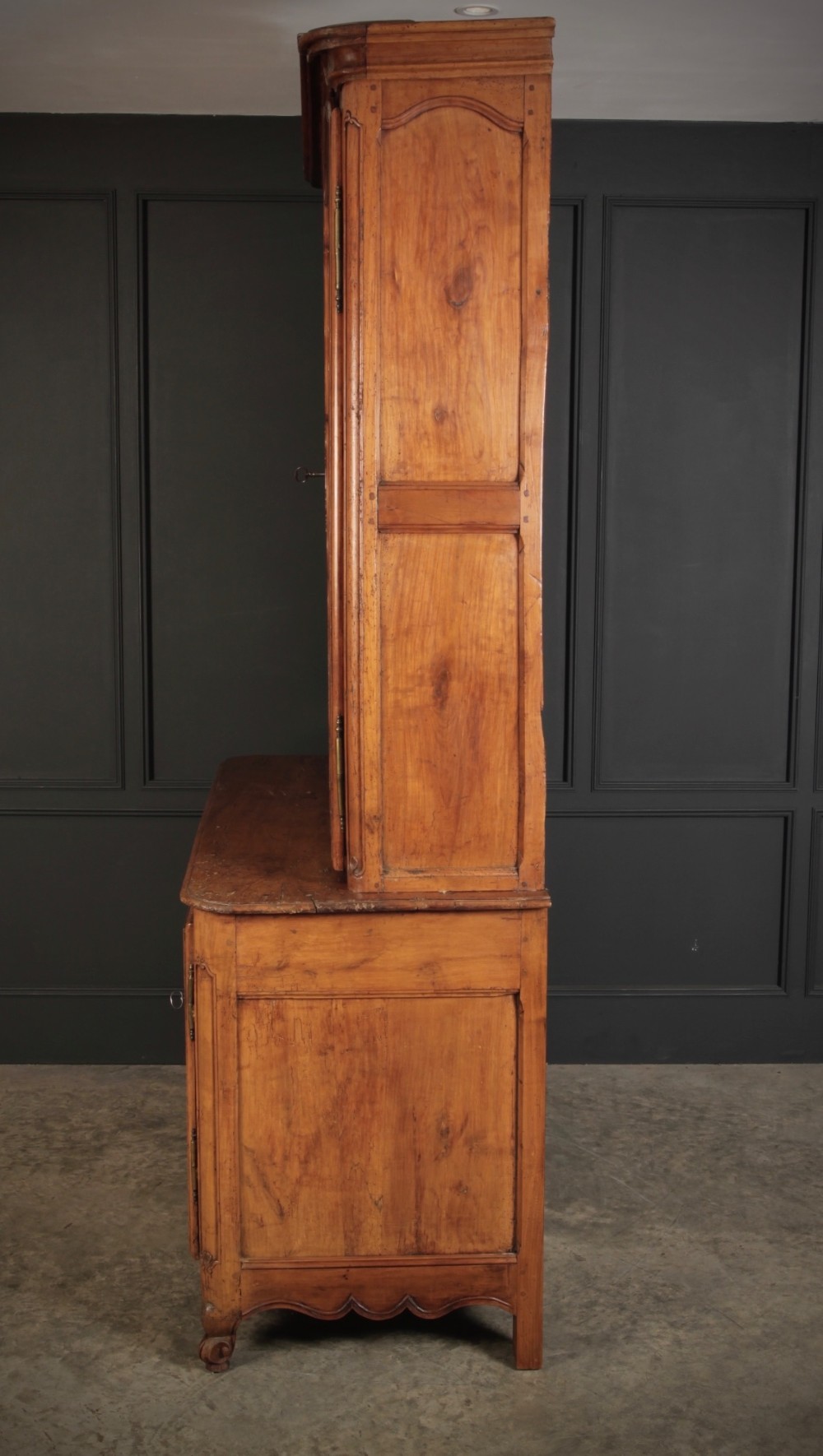 An 18th-century French Provincial two-tier cherry wood cupboard featuring moulded panel doors, long brass hinges, and a curved top cornice. View V