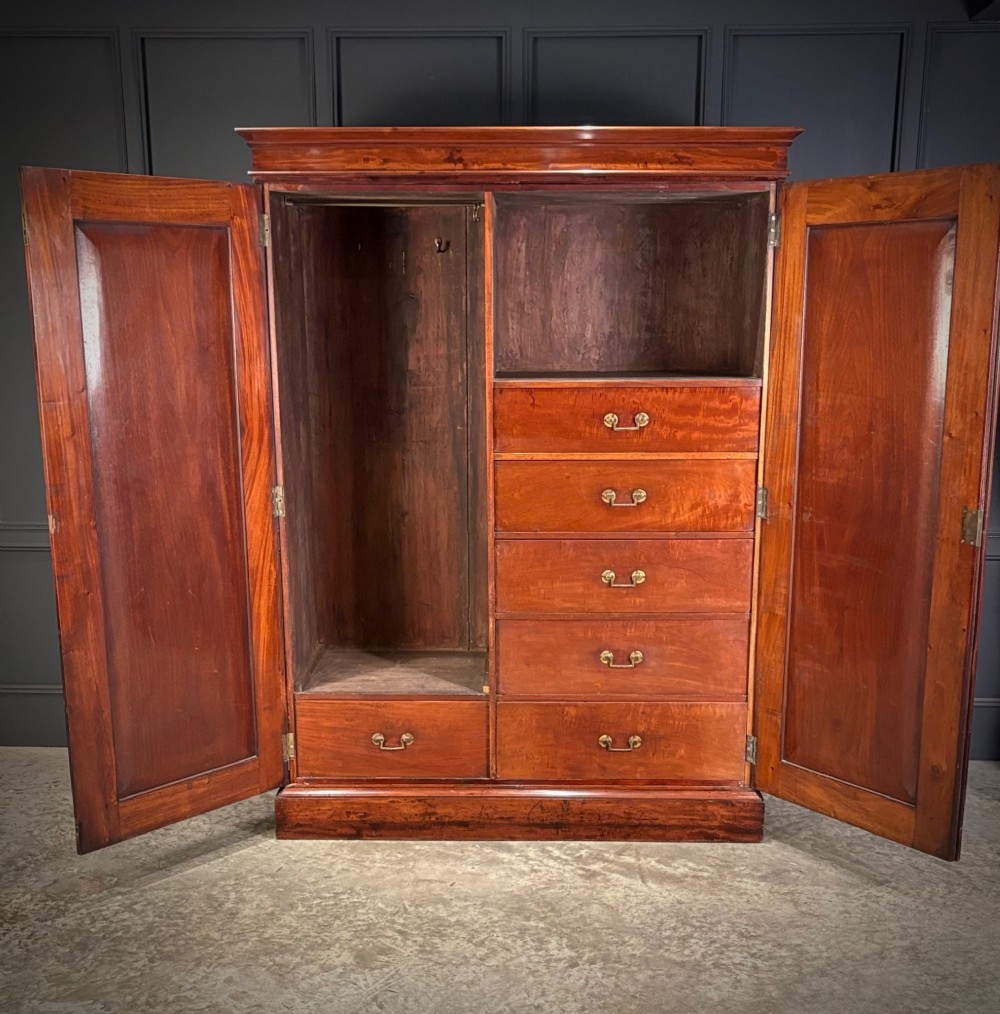 A two-door William IV mahogany wardrobe featuring flame mahogany panels, a moulded top cornice, and a sturdy plinth base. View II