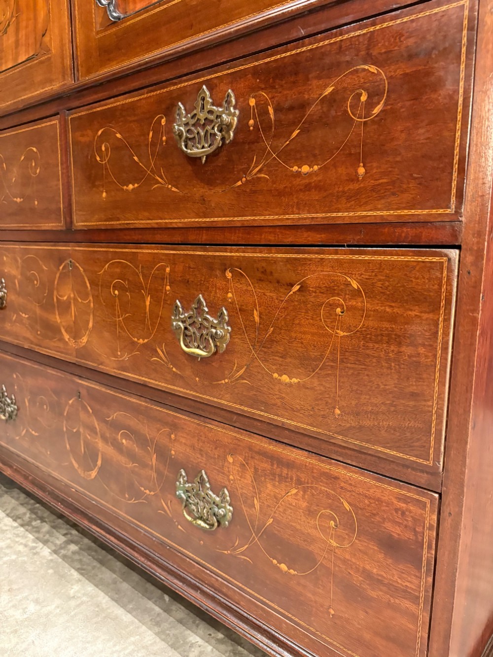 A Georgian mahogany linen press featuring botanical marquetry inlay on upper double doors over four lower drawers with brass handles. View III