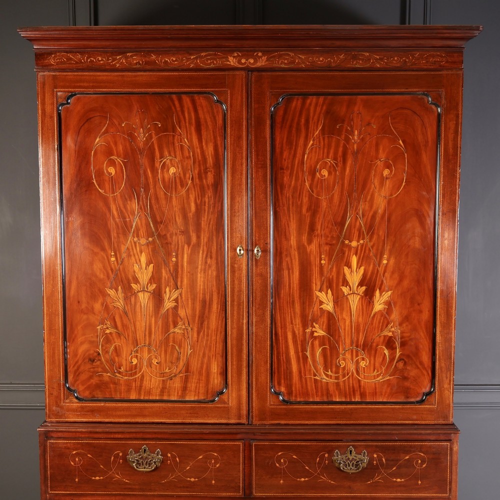 A Georgian mahogany linen press featuring botanical marquetry inlay on upper double doors over four lower drawers with brass handles. View VI
