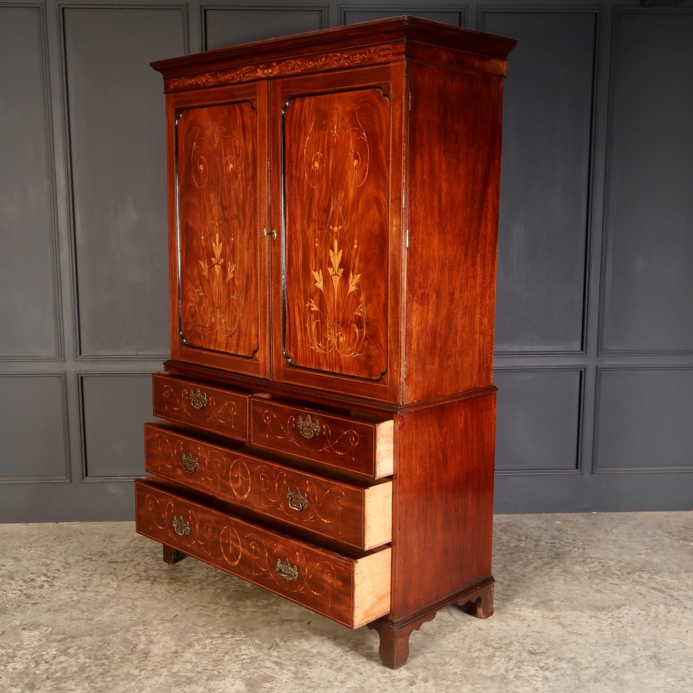 A Georgian mahogany linen press featuring botanical marquetry inlay on upper double doors over four lower drawers with brass handles. View VII