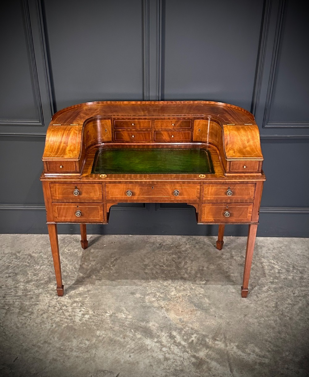 An inlaid mahogany Carlton House writing desk featuring a curved gallery with small drawers and cupboards above a green leather writing surface and square tapered legs. View III