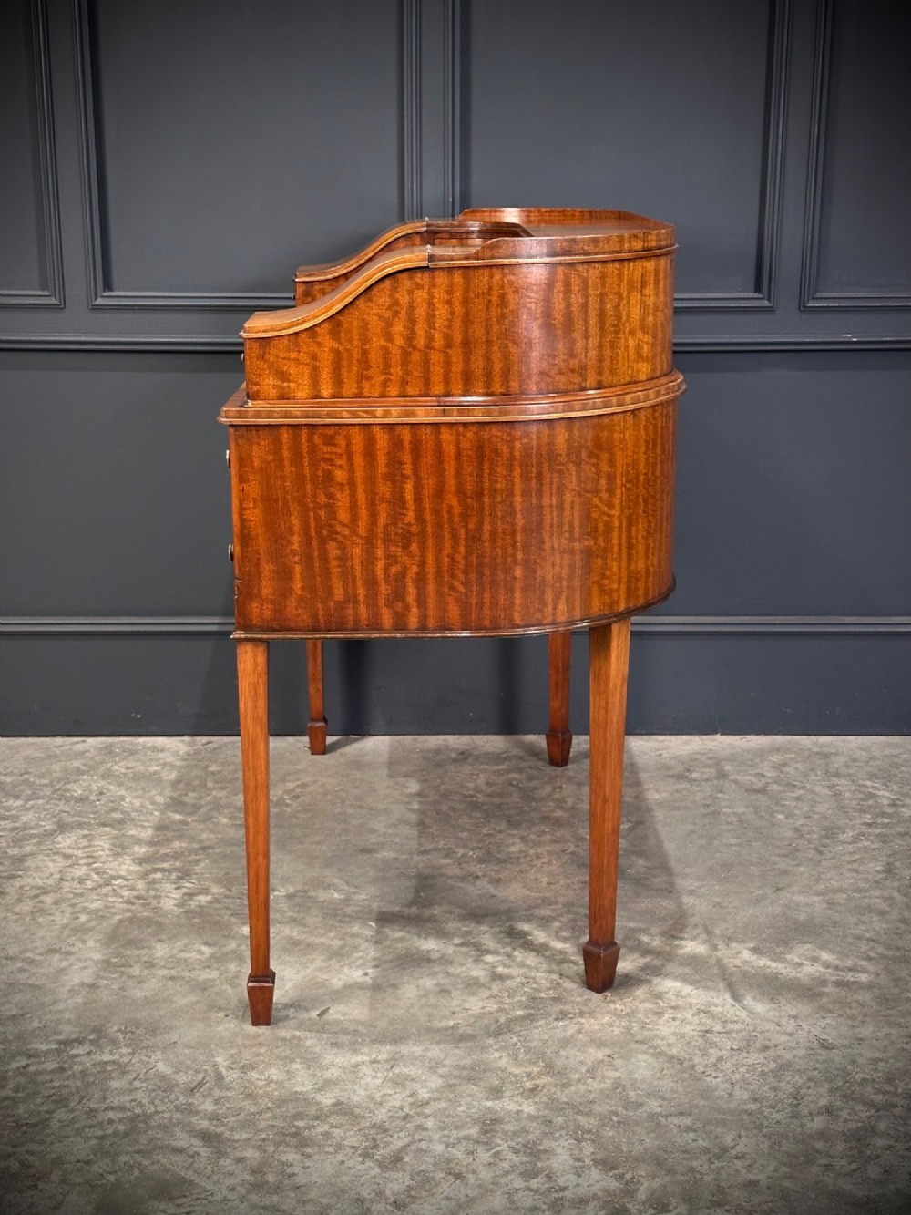 An inlaid mahogany Carlton House writing desk featuring a curved gallery with small drawers and cupboards above a green leather writing surface and square tapered legs. View X