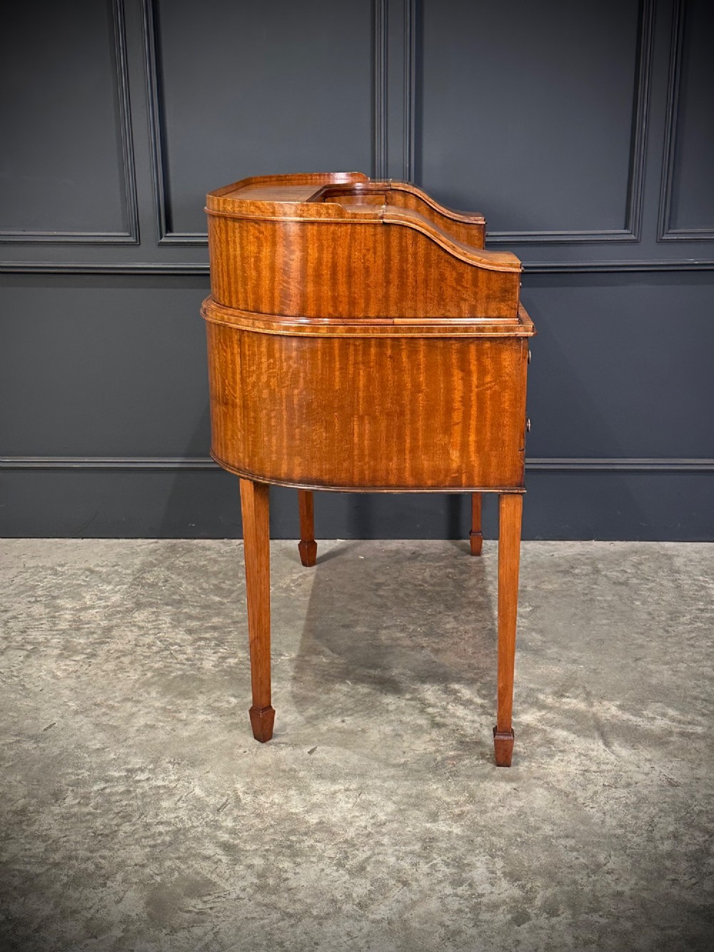 An inlaid mahogany Carlton House writing desk featuring a curved gallery with small drawers and cupboards above a green leather writing surface and square tapered legs. View XII