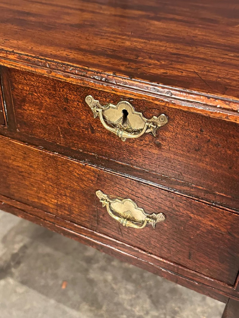 A Queen Anne dark oak lowboy featuring three drawers with brass backplate handles resting on slender cabriole legs with pad feet. View VIII