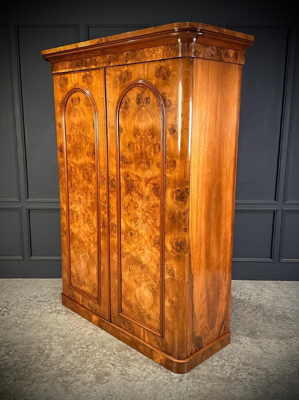 A Victorian double-door wardrobe crafted from figured burr walnut featuring arched door panels and a rounded moulded cornice. View V