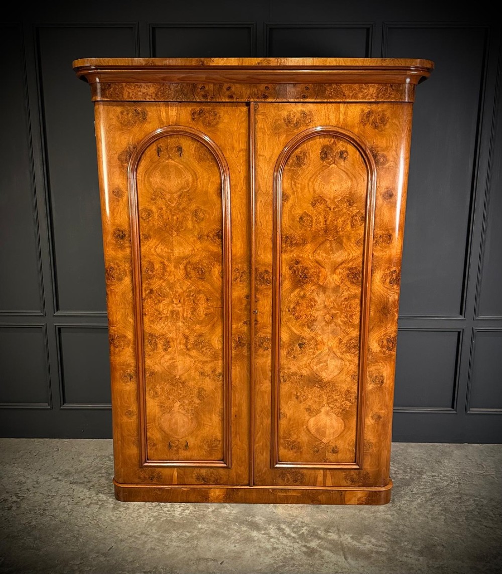 A Victorian double-door wardrobe crafted from figured burr walnut featuring arched door panels and a rounded moulded cornice. View VII