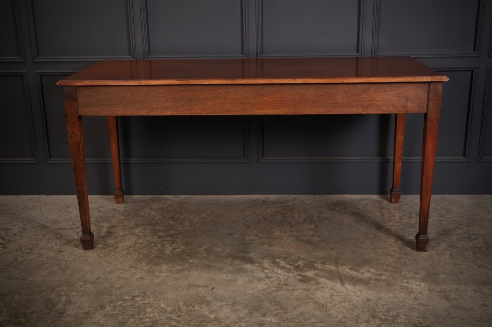 A large Sheraton style mahogany serving table featuring a rectangular top, frieze carved with drapery swags and a central urn relief, supported by four tapered fluted legs. View XI