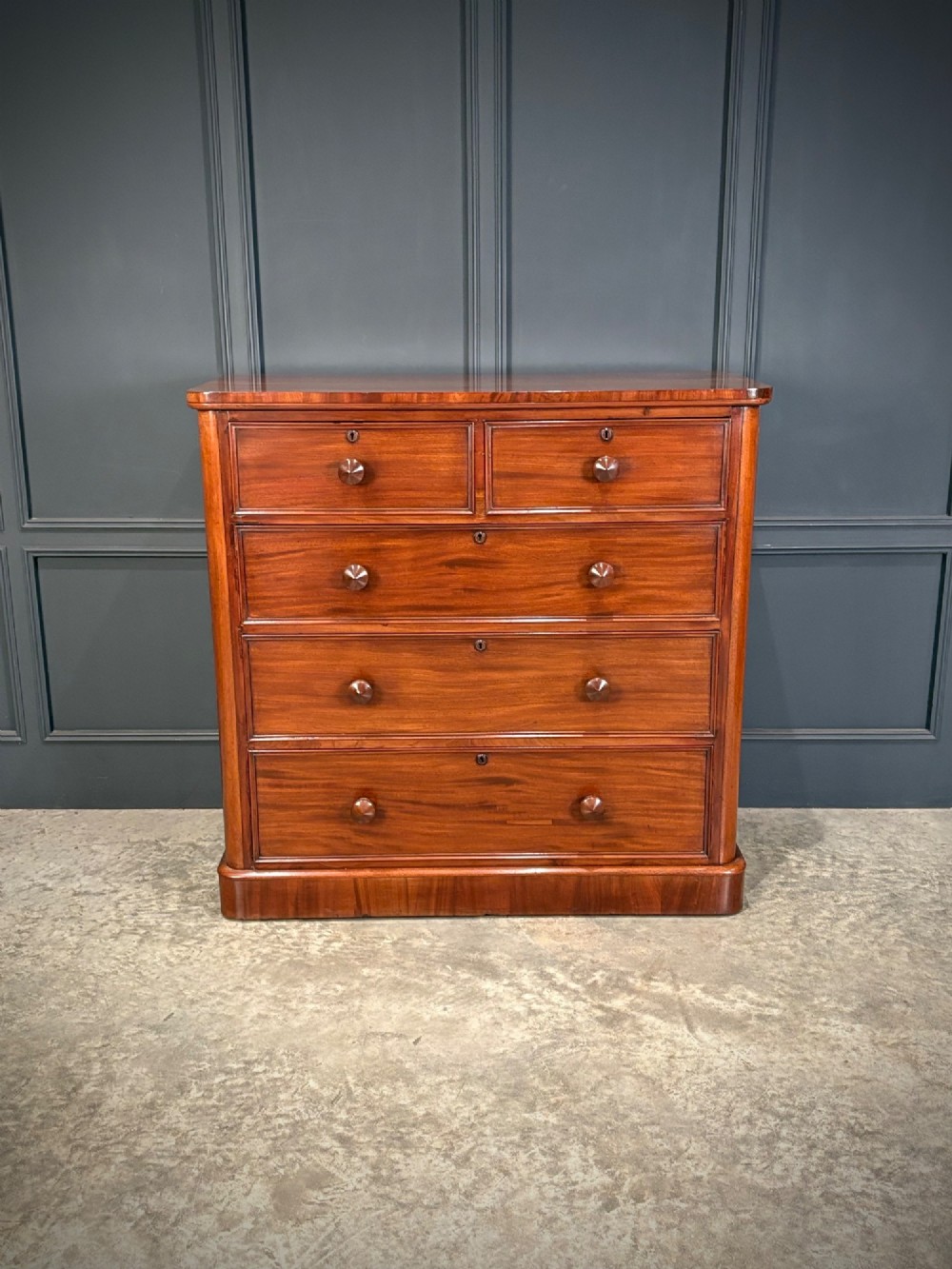 A Victorian mahogany chest of drawers with a two-over-three drawer arrangement, turned wooden knobs, rounded front corners, and a solid plinth base. View II