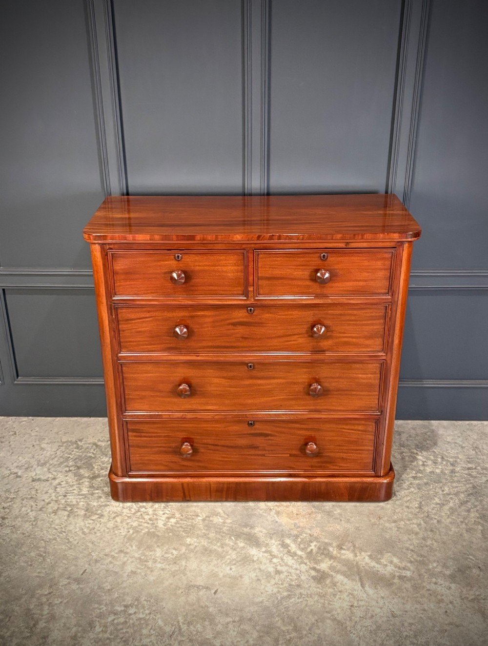 A Victorian mahogany chest of drawers with a two-over-three drawer arrangement, turned wooden knobs, rounded front corners, and a solid plinth base. View III