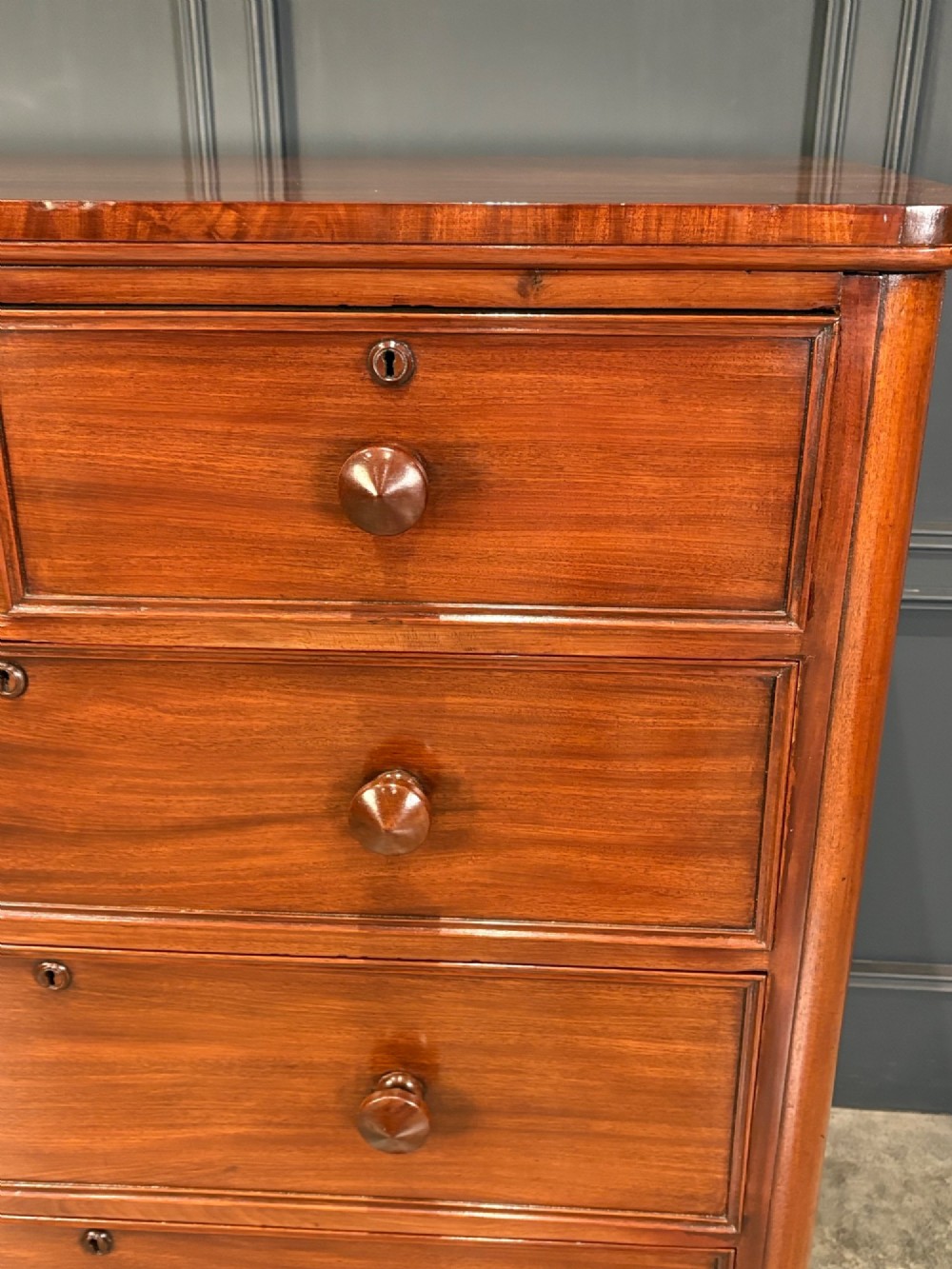 A Victorian mahogany chest of drawers with a two-over-three drawer arrangement, turned wooden knobs, rounded front corners, and a solid plinth base. View IV