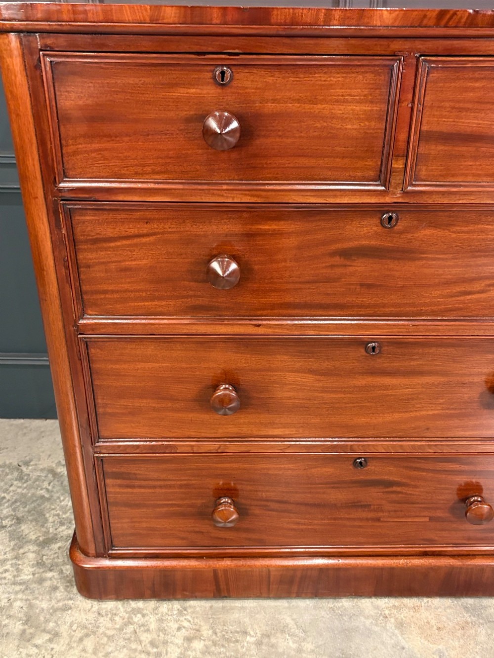 A Victorian mahogany chest of drawers with a two-over-three drawer arrangement, turned wooden knobs, rounded front corners, and a solid plinth base. View V