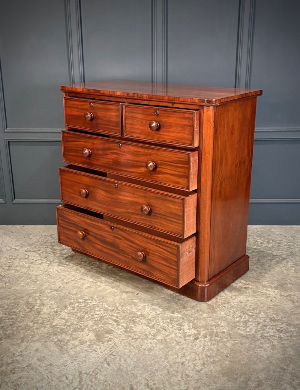 A Victorian mahogany chest of drawers with a two-over-three drawer arrangement, turned wooden knobs, rounded front corners, and a solid plinth base. View VI