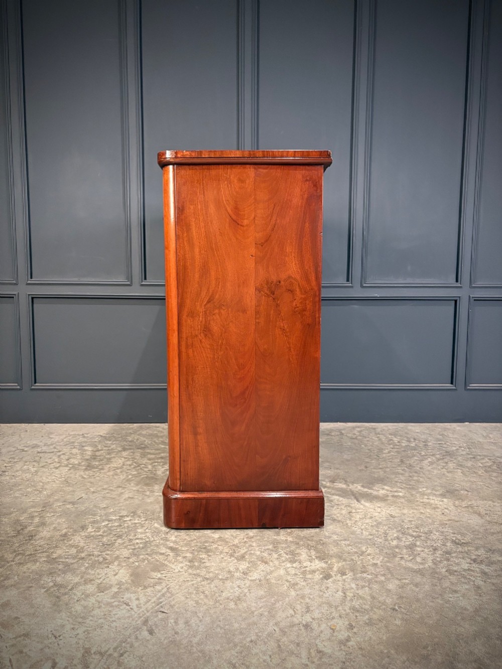 A Victorian mahogany chest of drawers with a two-over-three drawer arrangement, turned wooden knobs, rounded front corners, and a solid plinth base. View IX