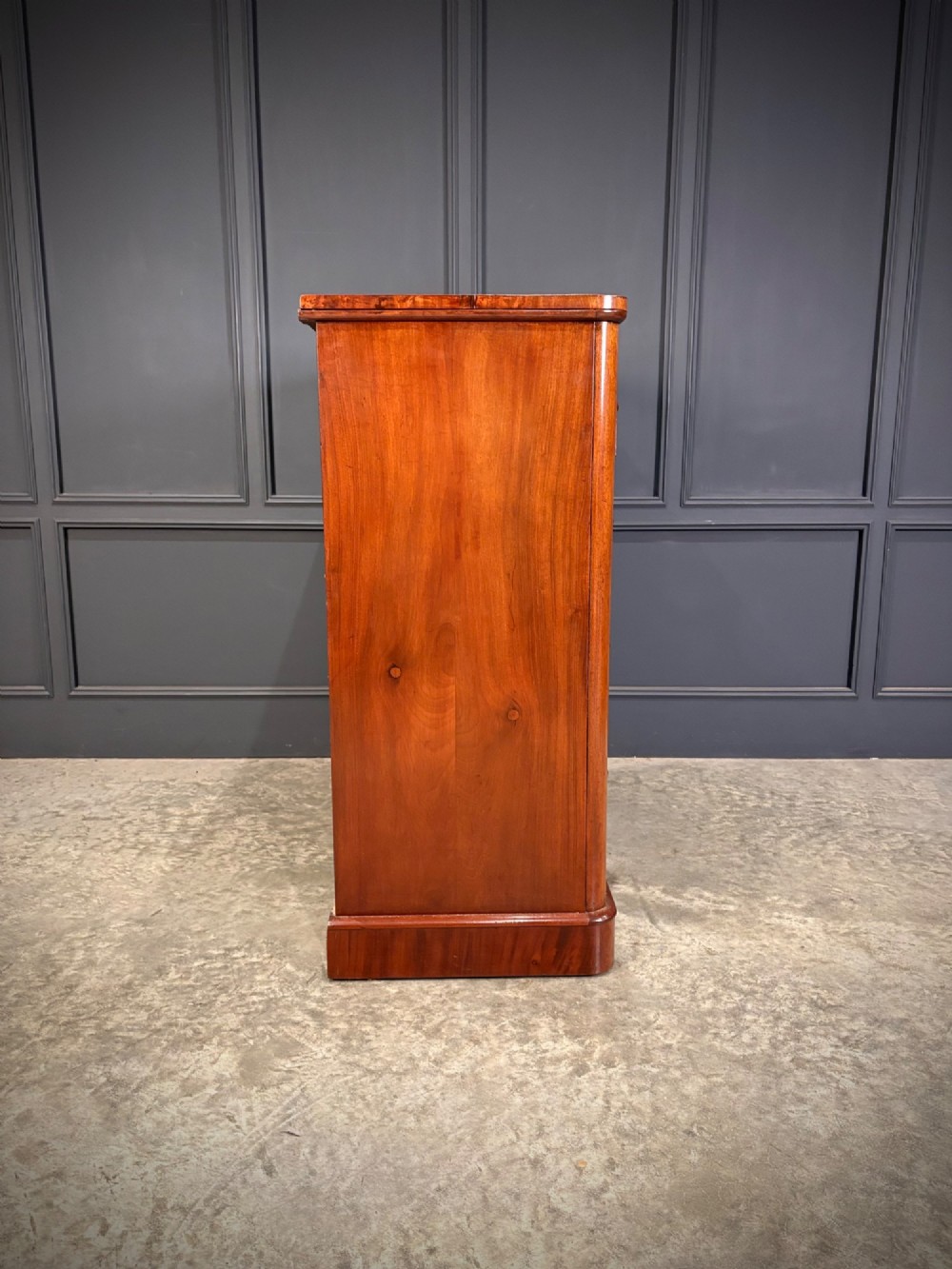 A Victorian mahogany chest of drawers with a two-over-three drawer arrangement, turned wooden knobs, rounded front corners, and a solid plinth base. View XI