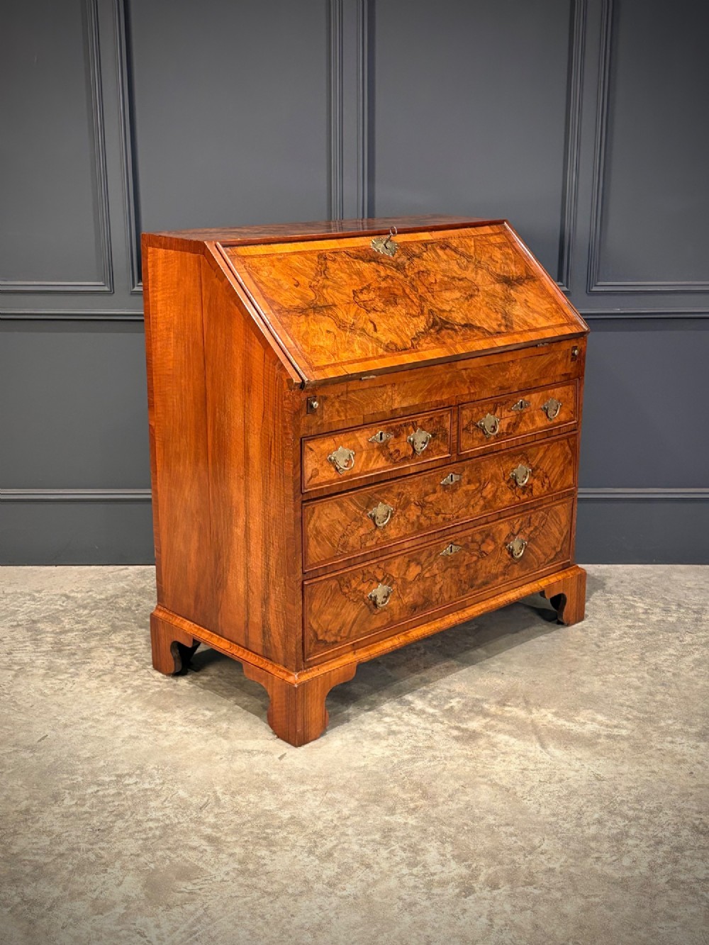 A Queen Anne style writing bureau crafted from figured walnut with a slant front writing flap above two short and two long drawers. View II