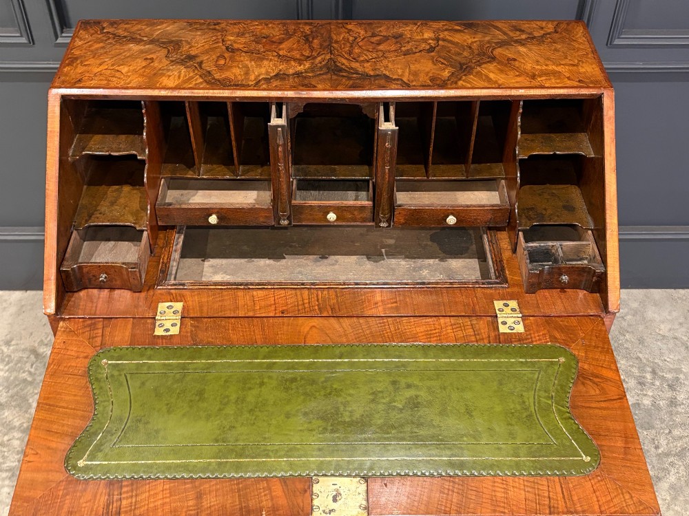 A Queen Anne style writing bureau crafted from figured walnut with a slant front writing flap above two short and two long drawers. View VI