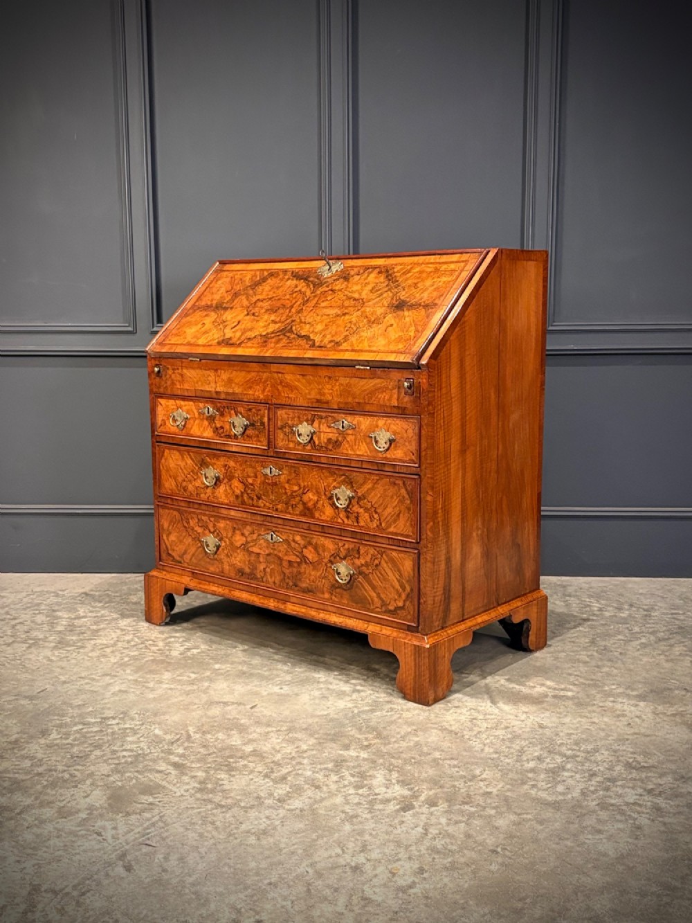A Queen Anne style writing bureau crafted from figured walnut with a slant front writing flap above two short and two long drawers.