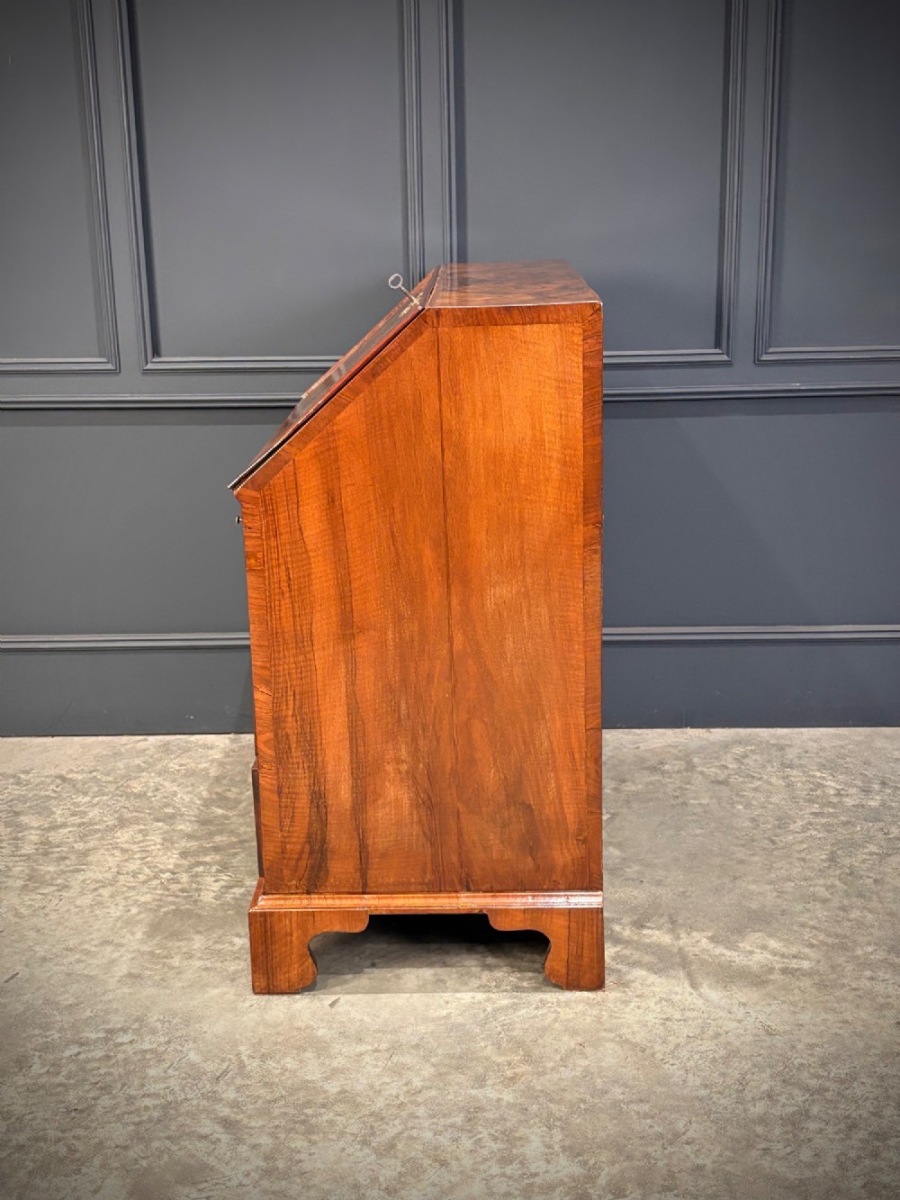 A Queen Anne style writing bureau crafted from figured walnut with a slant front writing flap above two short and two long drawers. View VIII