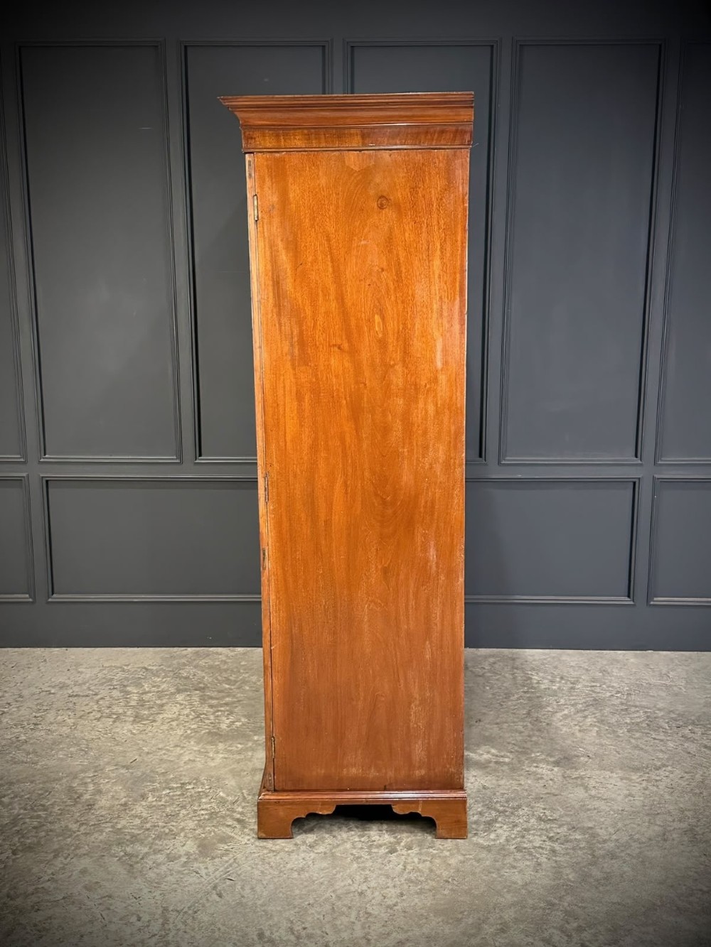 A tall Georgian style mahogany double wardrobe featuring flame mahogany door panels, a moulded cornice, and bracket feet. View III