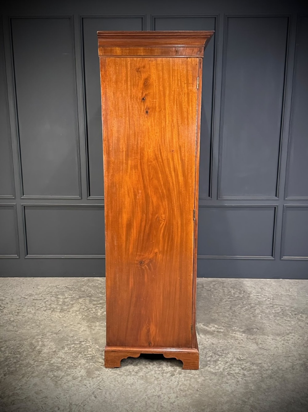 A tall Georgian style mahogany double wardrobe featuring flame mahogany door panels, a moulded cornice, and bracket feet. View V