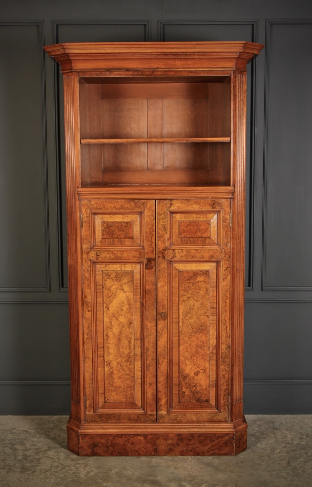 A tall Victorian burr walnut bookcase featuring open upper shelving over a double-door lower cupboard with fluted side pilasters. View II