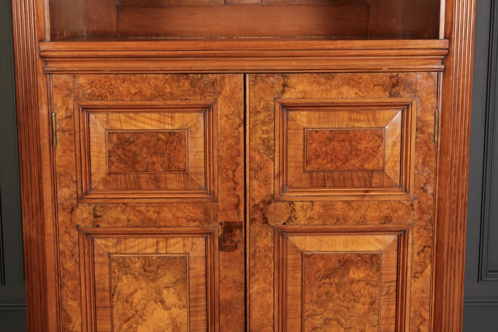 A tall Victorian burr walnut bookcase featuring open upper shelving over a double-door lower cupboard with fluted side pilasters. View V