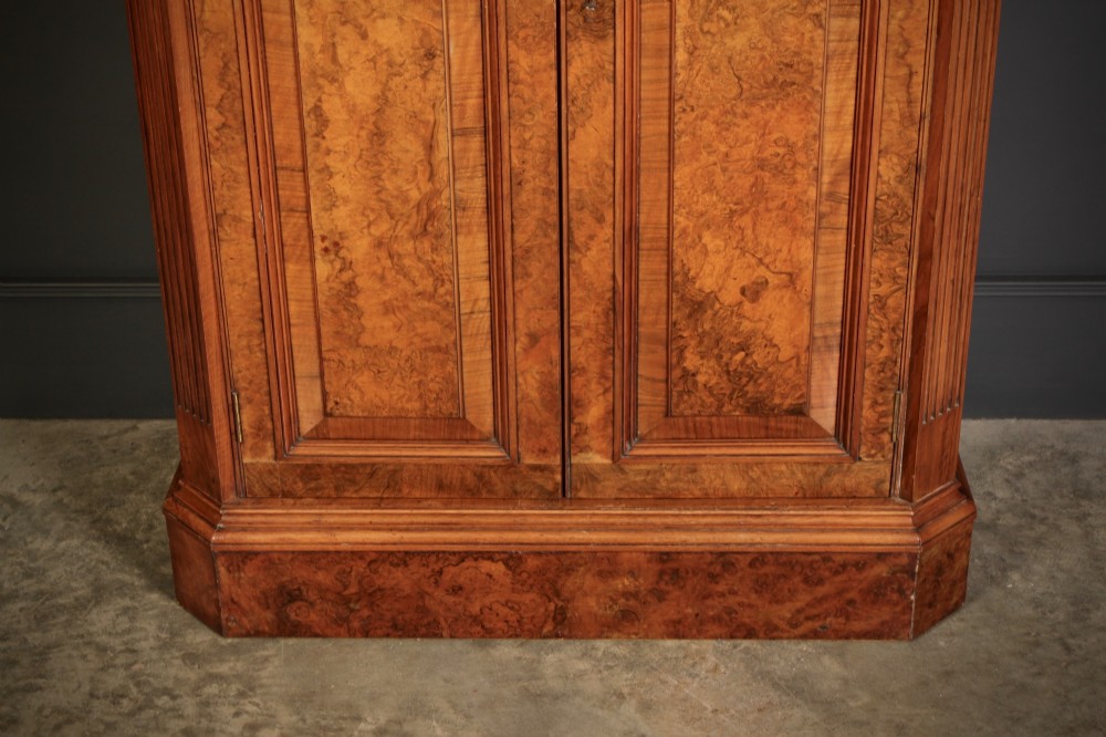 A tall Victorian burr walnut bookcase featuring open upper shelving over a double-door lower cupboard with fluted side pilasters. View VII