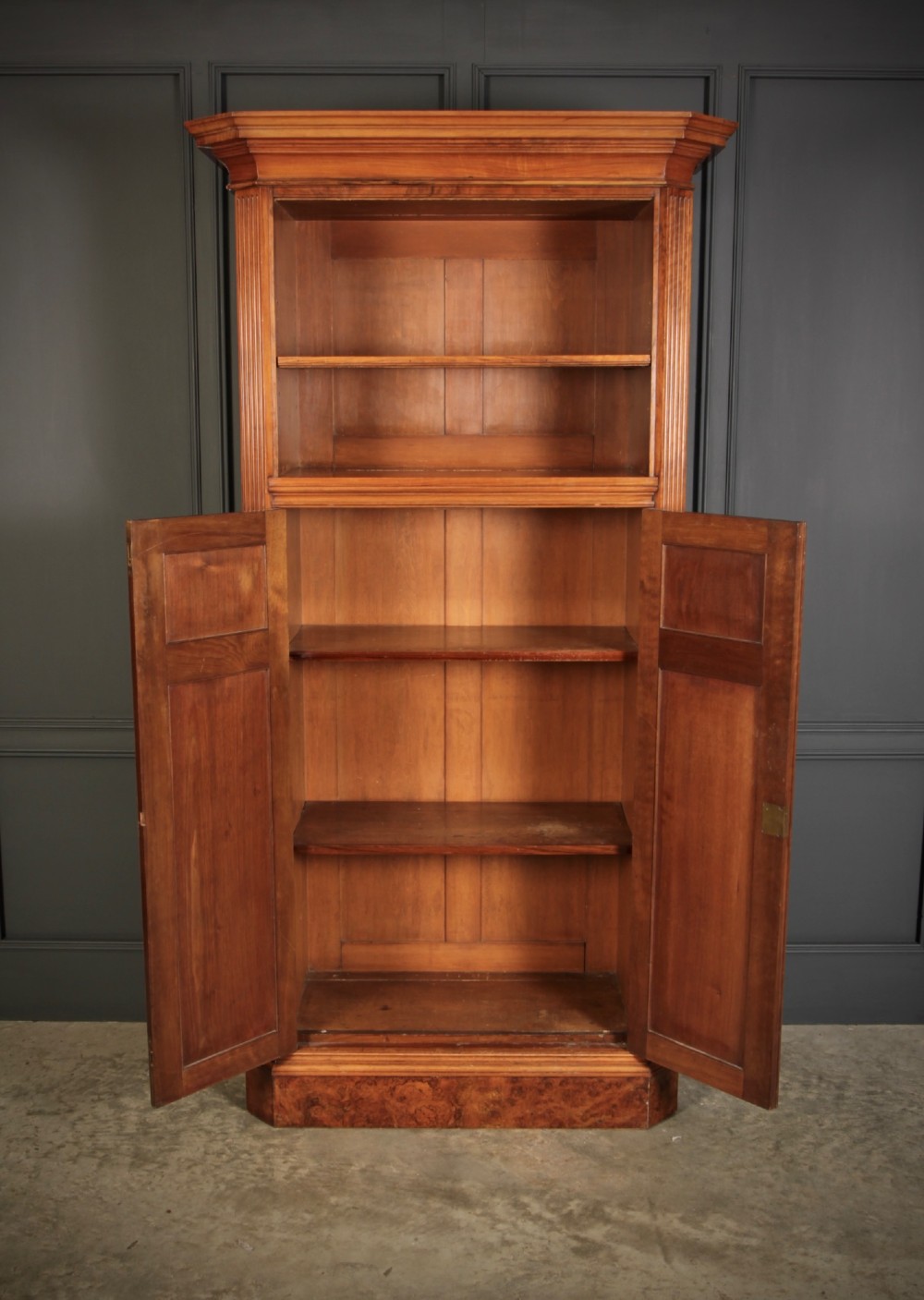 A tall Victorian burr walnut bookcase featuring open upper shelving over a double-door lower cupboard with fluted side pilasters. View VIII