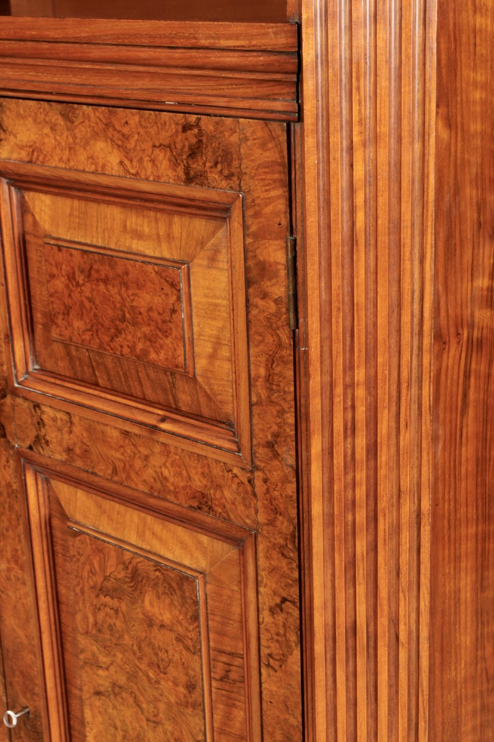 A tall Victorian burr walnut bookcase featuring open upper shelving over a double-door lower cupboard with fluted side pilasters. View XI