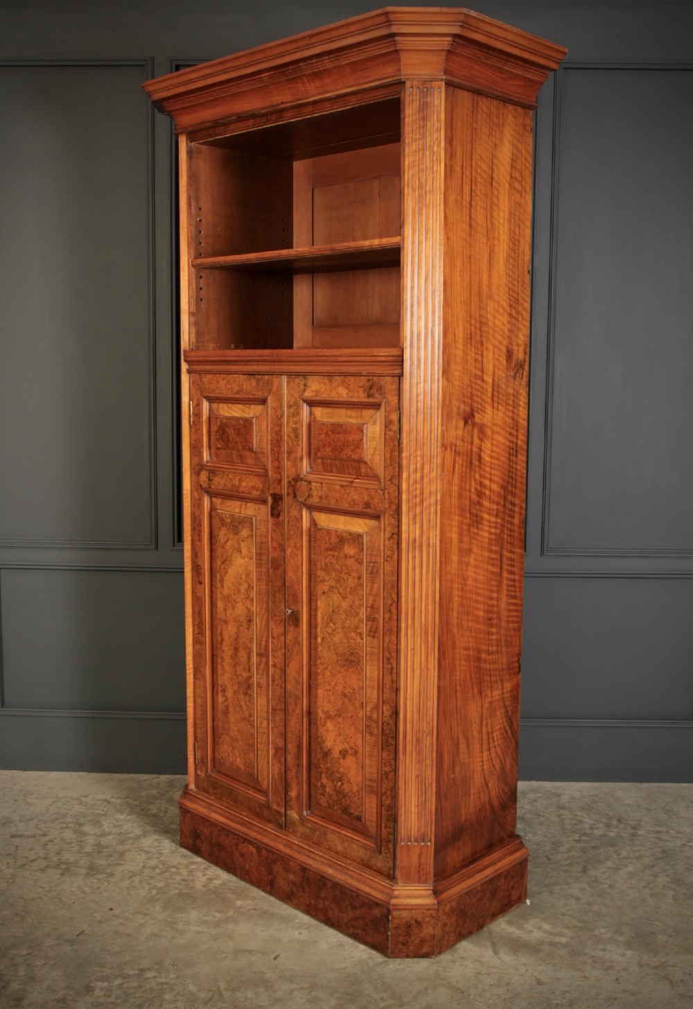 A tall Victorian burr walnut bookcase featuring open upper shelving over a double-door lower cupboard with fluted side pilasters. View XII