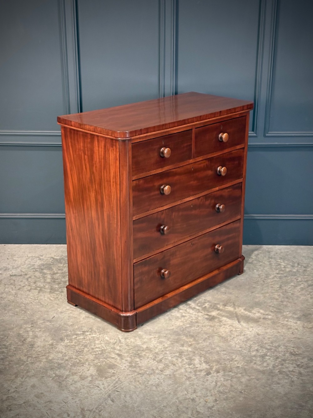 A Victorian mahogany chest of drawers with two short drawers over three long drawers, featuring turned wooden handles and a solid plinth base. View II