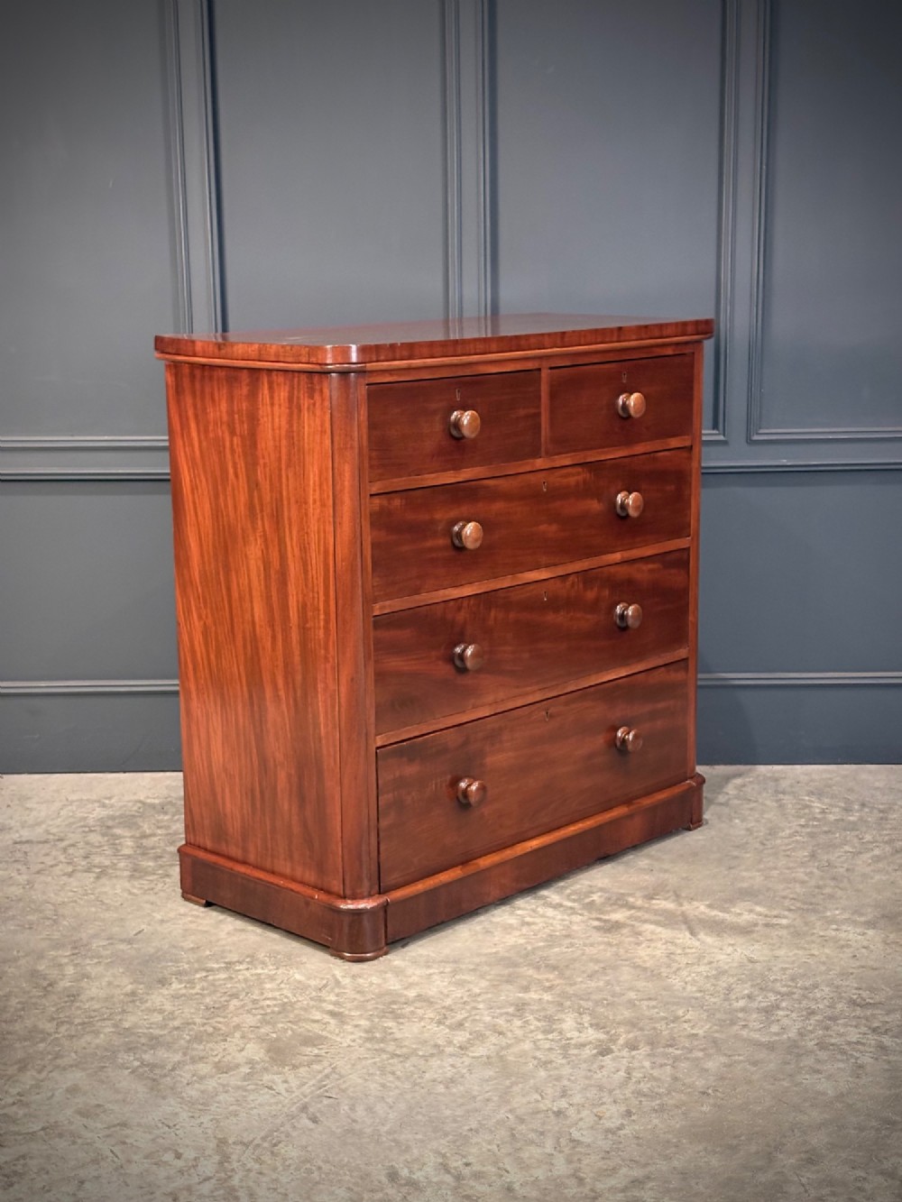 A Victorian mahogany chest of drawers with two short drawers over three long drawers, featuring turned wooden handles and a solid plinth base.