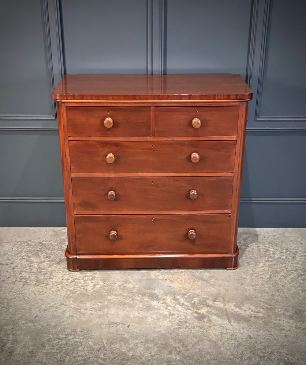 A Victorian mahogany chest of drawers with two short drawers over three long drawers, featuring turned wooden handles and a solid plinth base. View III