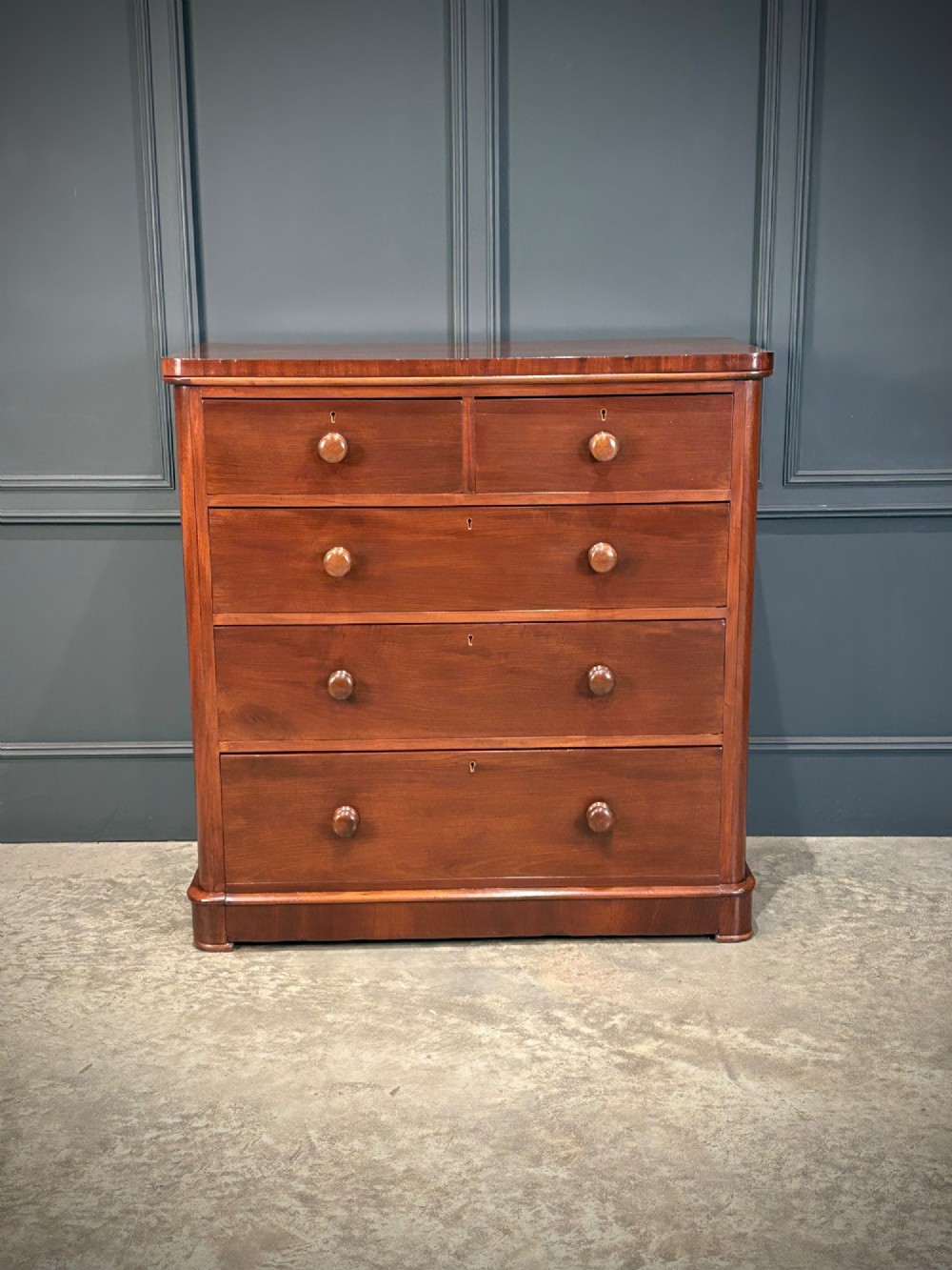 A Victorian mahogany chest of drawers with two short drawers over three long drawers, featuring turned wooden handles and a solid plinth base. View IV