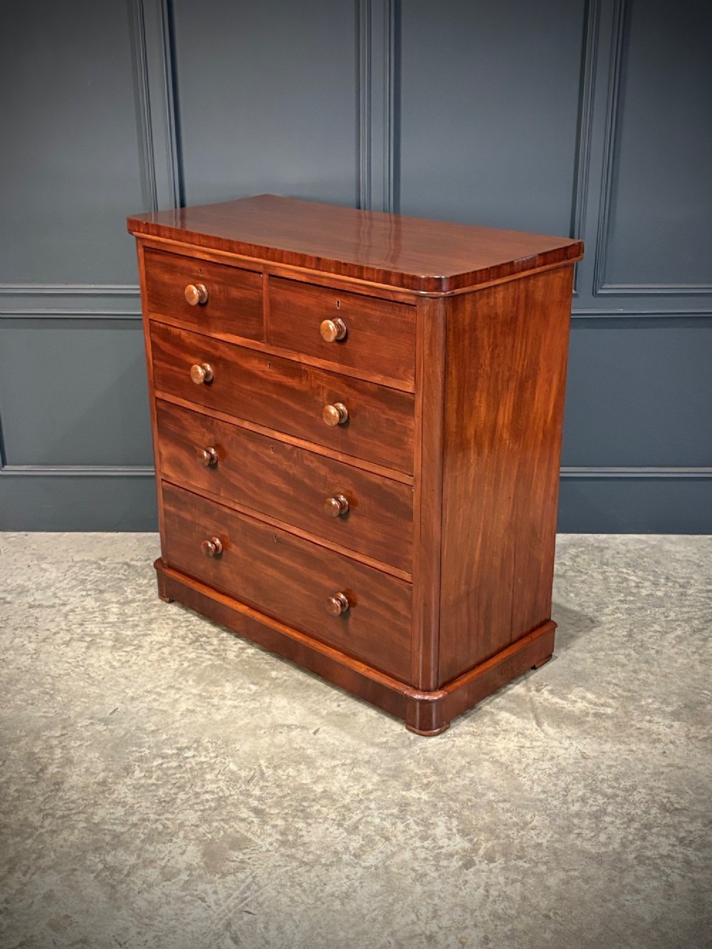 A Victorian mahogany chest of drawers with two short drawers over three long drawers, featuring turned wooden handles and a solid plinth base. View V