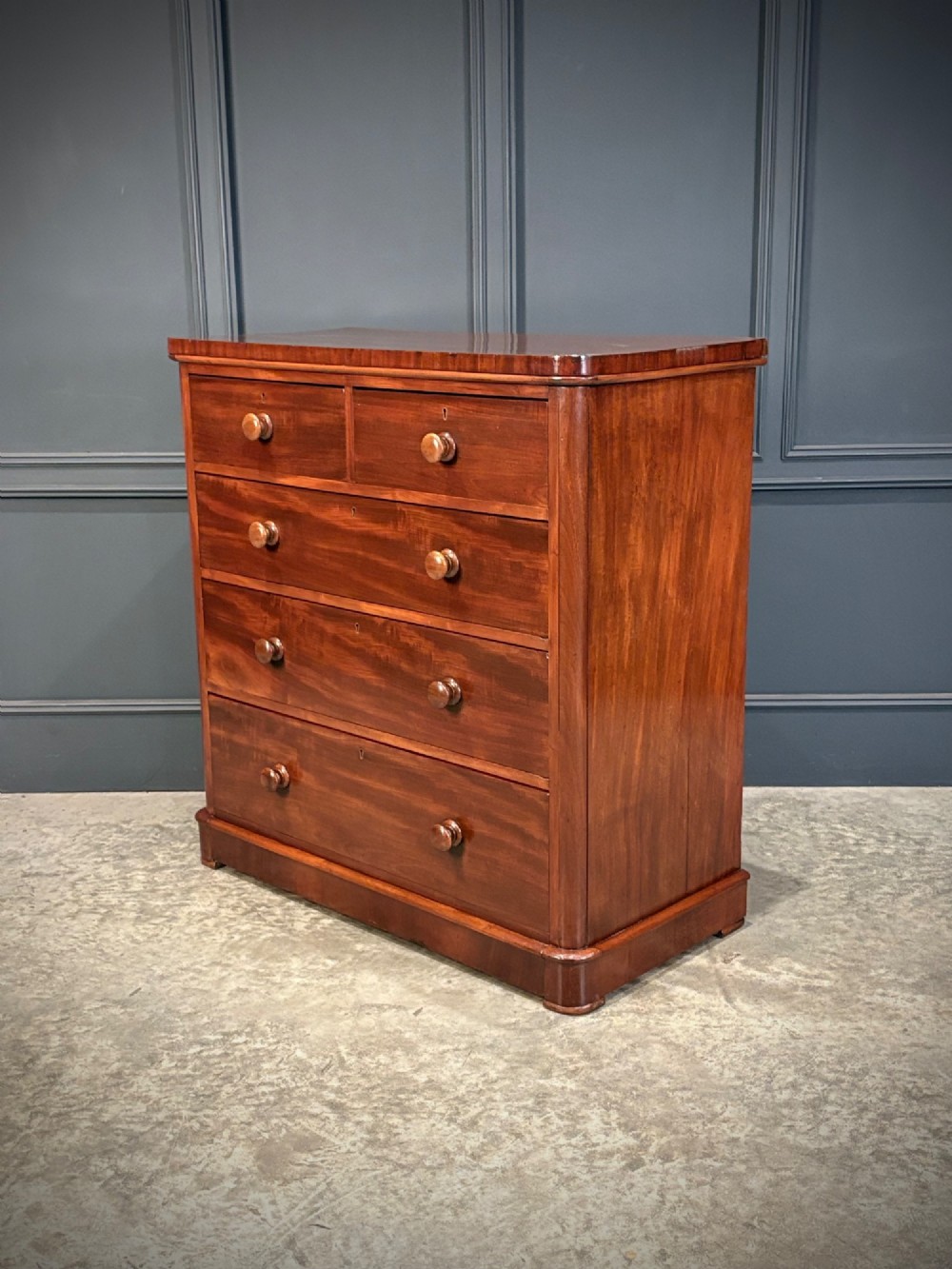 A Victorian mahogany chest of drawers with two short drawers over three long drawers, featuring turned wooden handles and a solid plinth base. View VI
