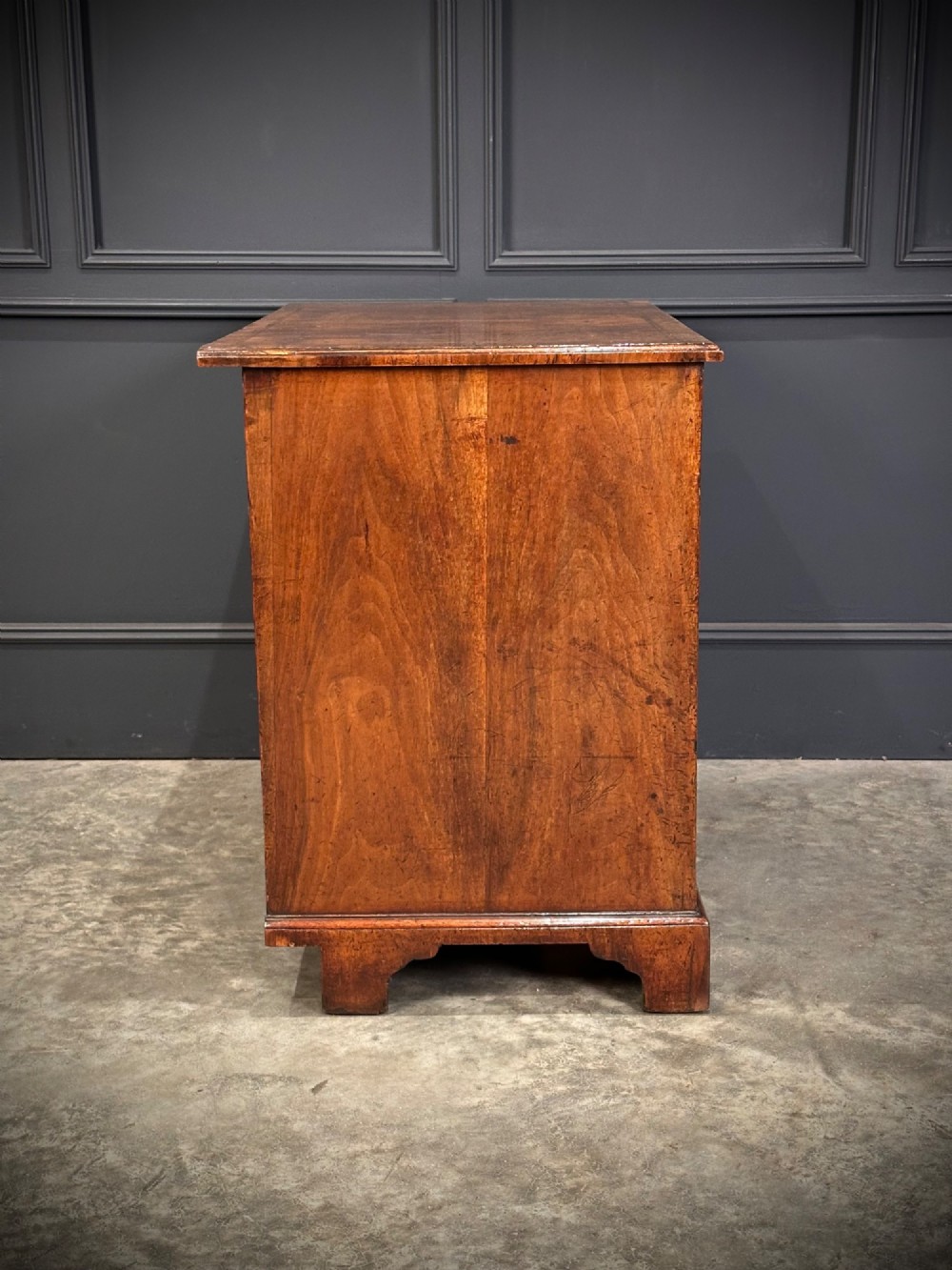 An 18th-century walnut kneehole desk featuring a flat top, multiple small drawers with brass drop handles, a recessed central cupboard, and bracket feet. View XIV