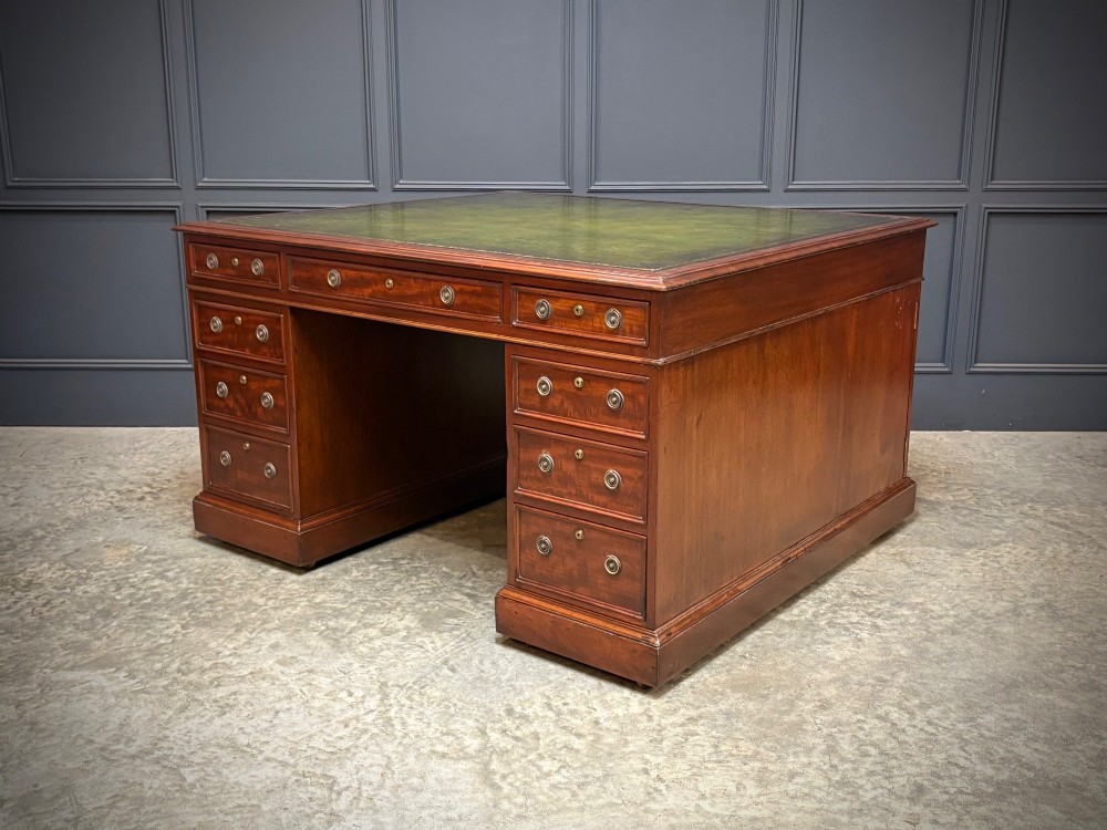 A large Victorian mahogany partners desk with a green leather inset top surface and twin pedestals fitted with wooden drawer pulls.