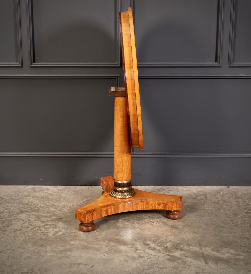 A circular antique satinwood occasional table featuring a crossbanded timber top, a central cylindrical pedestal with a brass mount, and a triform base on bun feet. View VI