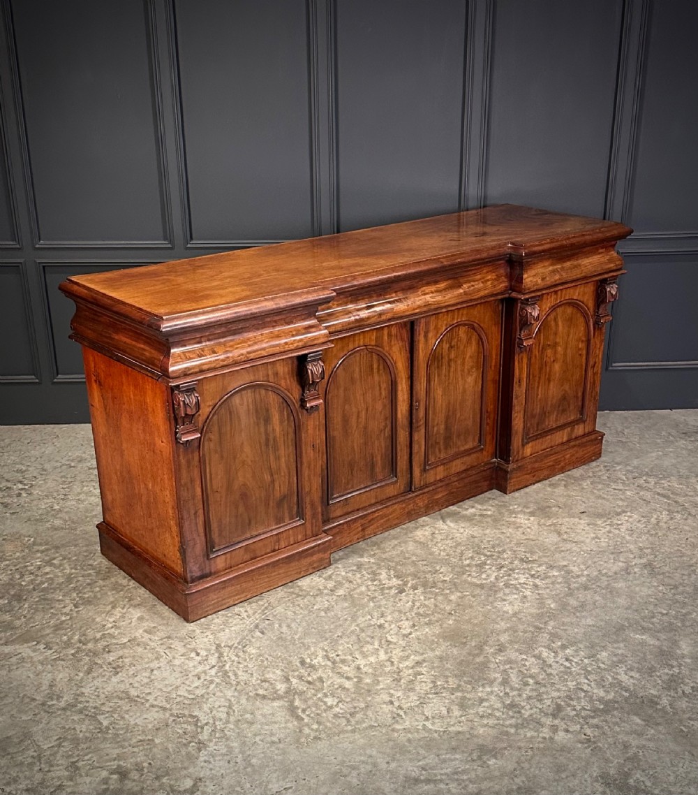 A Victorian mahogany four-door breakfront sideboard featuring arched panel doors, carved support brackets, and a long flat top surface. View III
